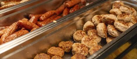 Un bufé con diferentes opciones de comida, incluyendo salchichas y albóndigas.