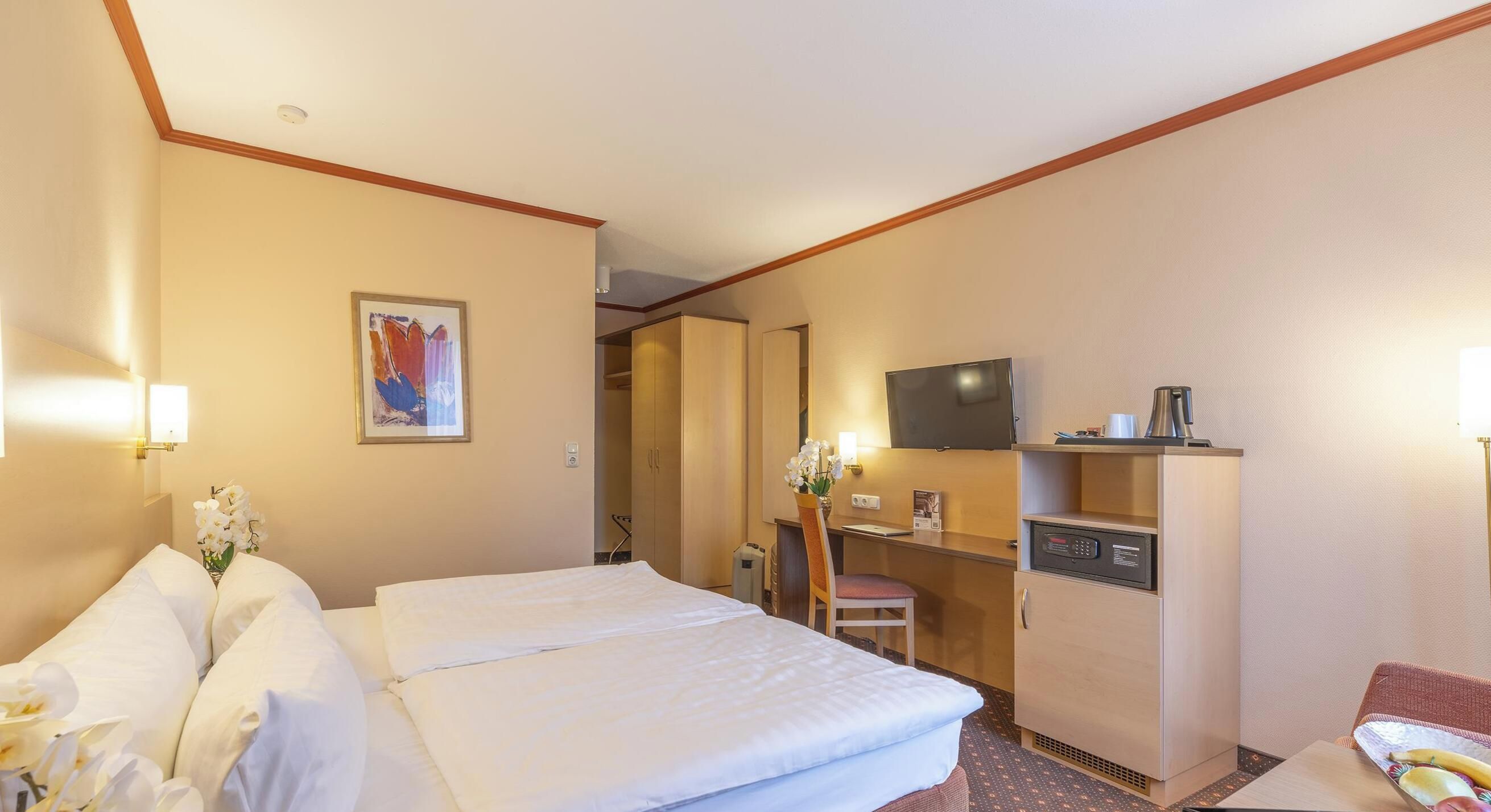 Una habitación de hotel con cama, escritorio, televisor y minibar.