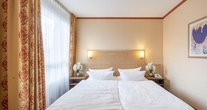 Een hotelkamer met een bed, twee nachtkastjes, een wandlamp en een schilderij.