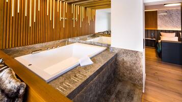 A modern bathroom with a large bathtub, a separate shower area, and a vanity with a mirror.