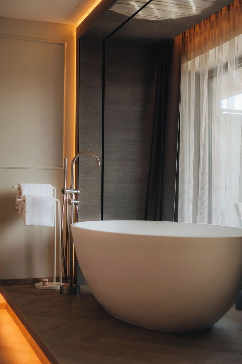 A modern bathroom with a freestanding bathtub, a towel rack, and a minimalist design.