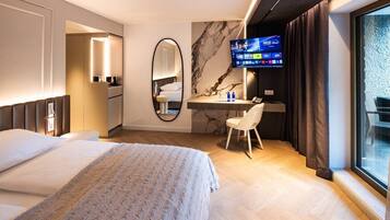 Ein Hotelzimmer mit Bett, Schreibtisch, Fernseher und einem großen Fenster.
