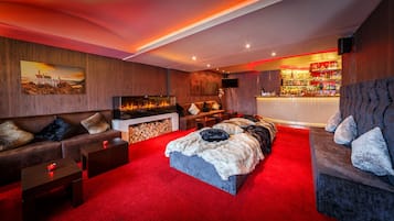 A cozy room with a fireplace, a bar, and a red carpet.
