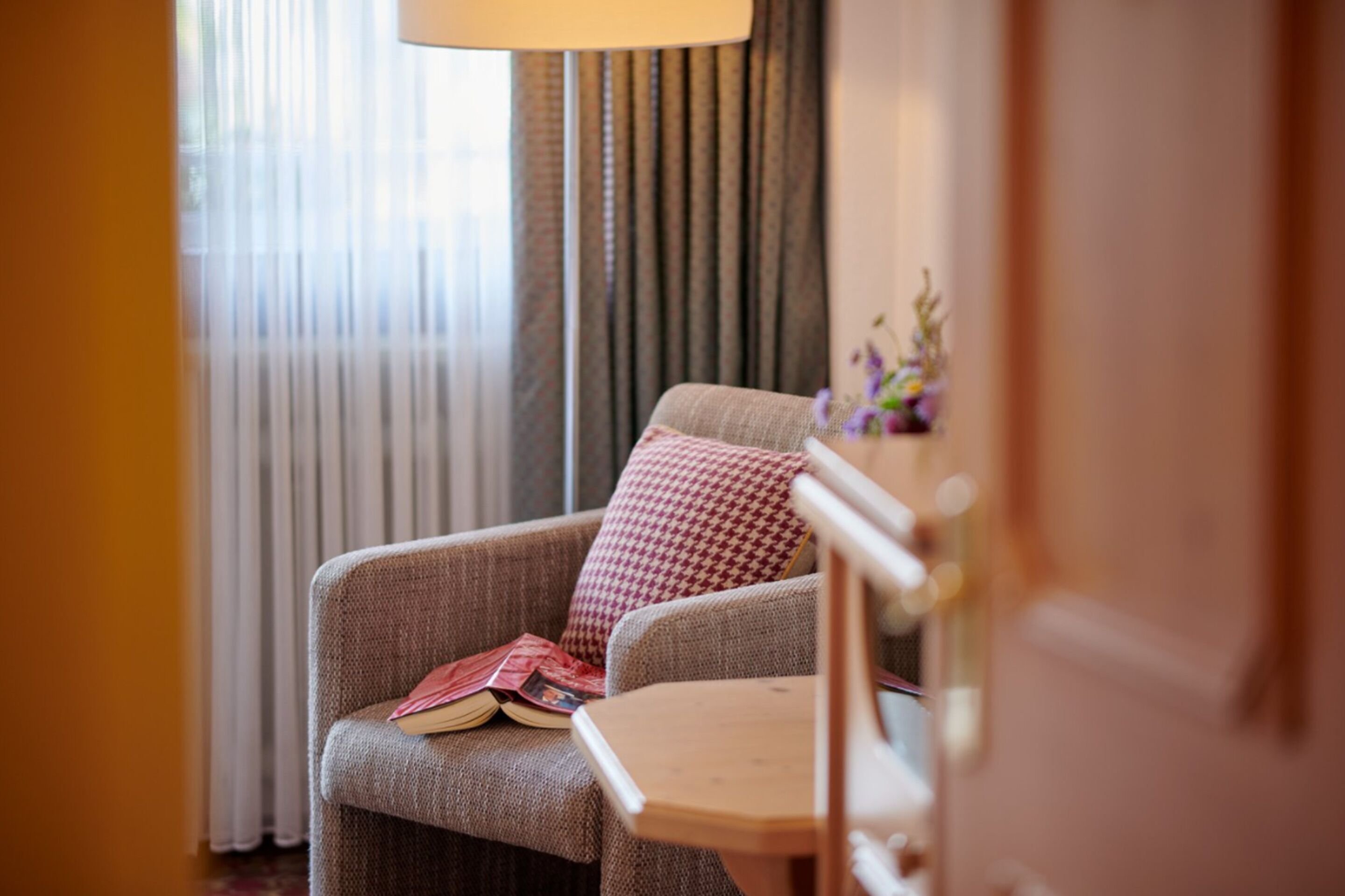 A cozy room with a chair, a small table, and a lamp.