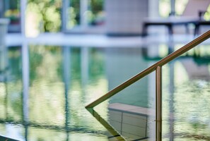 A clear view of a swimming pool with a glass barrier and metal railing. - Hotel Bannwaldsee (Halblech)