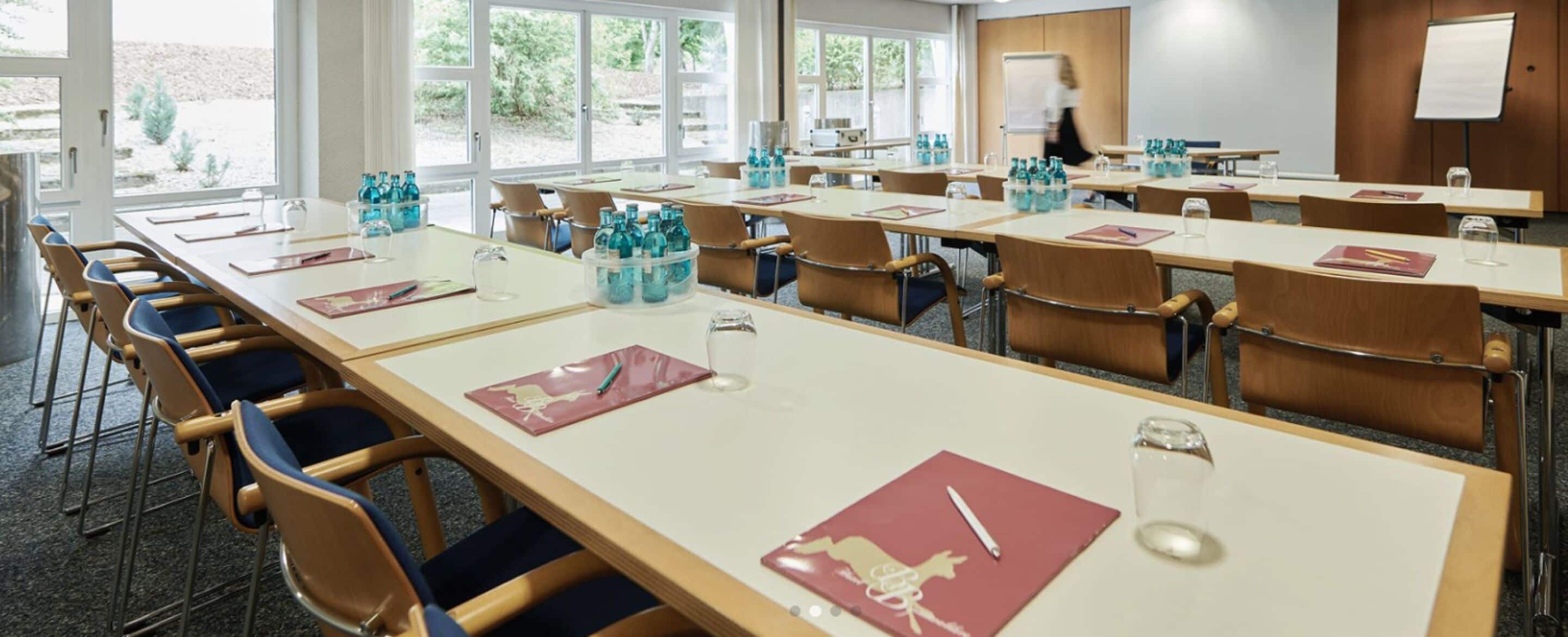 A conference room with long tables, chairs, water bottles, and a whiteboard.