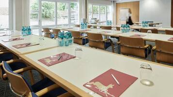 A conference room with long tables, chairs, water bottles, and a whiteboard.