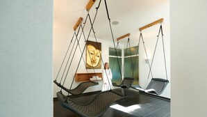 Una habitación con tres hamacas colgantes, una gran estatua de Buda y una persona vestida con túnica.