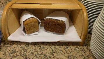 Una caja de madera para pan con dos hogazas dentro, sobre una encimera.