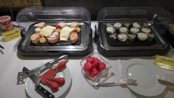 A buffet with various cheese and meat options, including red sausage.