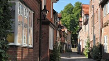A narrow cobblestone street lined with traditional brick buildings, featuring large windows and hanging lanterns.