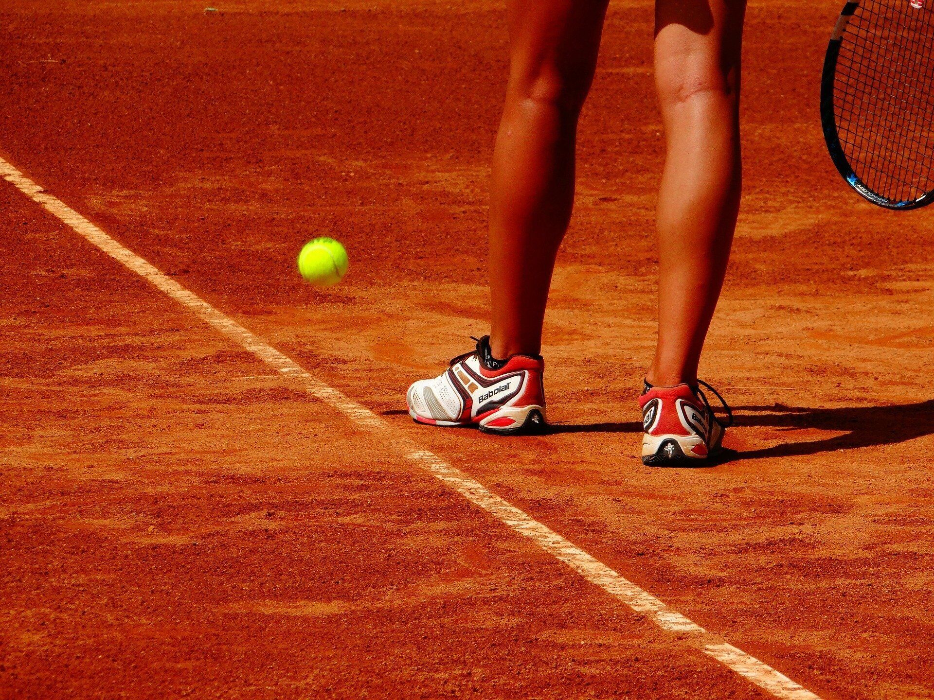 Un court de tennis avec une balle de tennis en mouvement et une raquette.