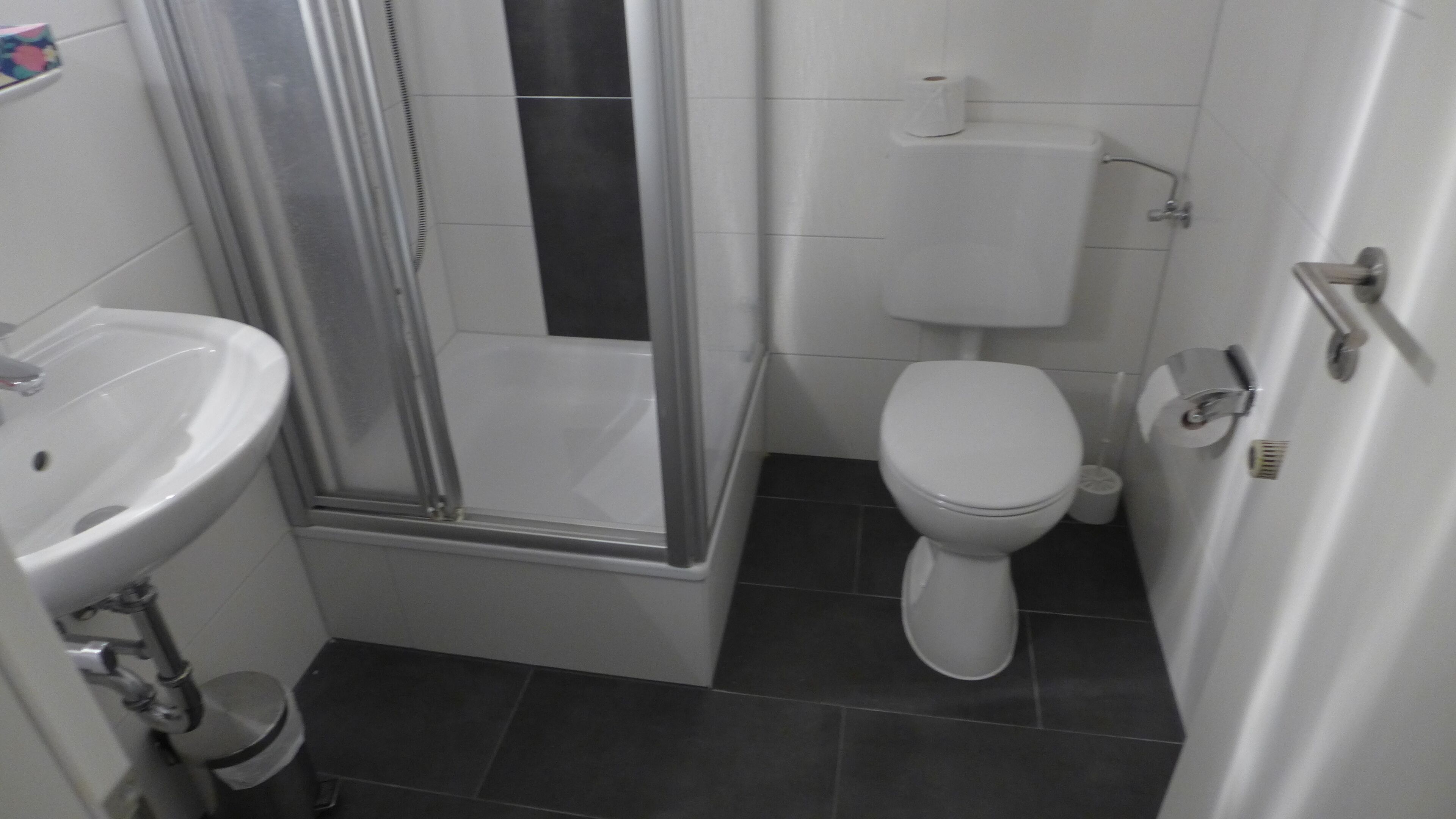 Un baño con lavamanos blanco, inodoro y cabina de ducha de cristal.
