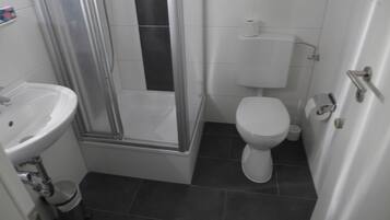 Un baño con lavamanos blanco, inodoro y cabina de ducha de cristal.