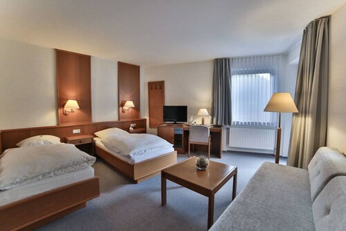 Une chambre d’hôtel avec deux lits, un bureau, une télévision et un canapé.