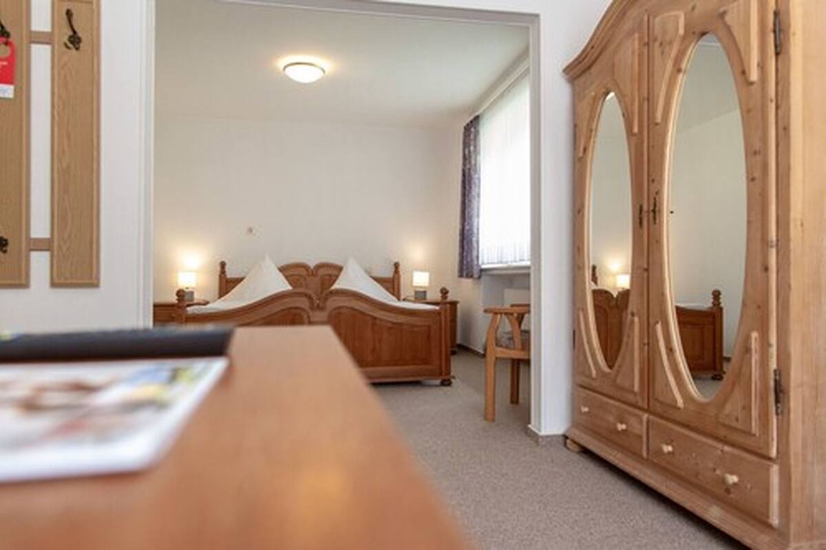 Une chambre à coucher avec un lit en bois, une commode et un miroir.