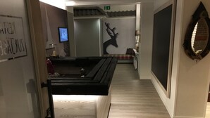 A hotel lobby with a wooden reception desk, a wall-mounted TV, and a deer silhouette decoration.