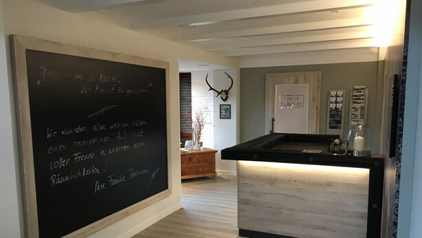 A kitchen with a chalkboard displaying text, a wooden cabinet, and a door with a sign.