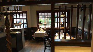 A restaurant with a wooden interior, large windows, and a dining area with tables and chairs.