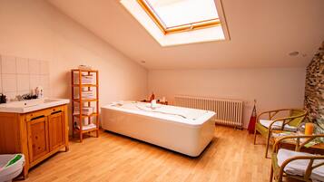 Un baño con tragaluz, bañera, armarios de madera y una silla de mimbre.