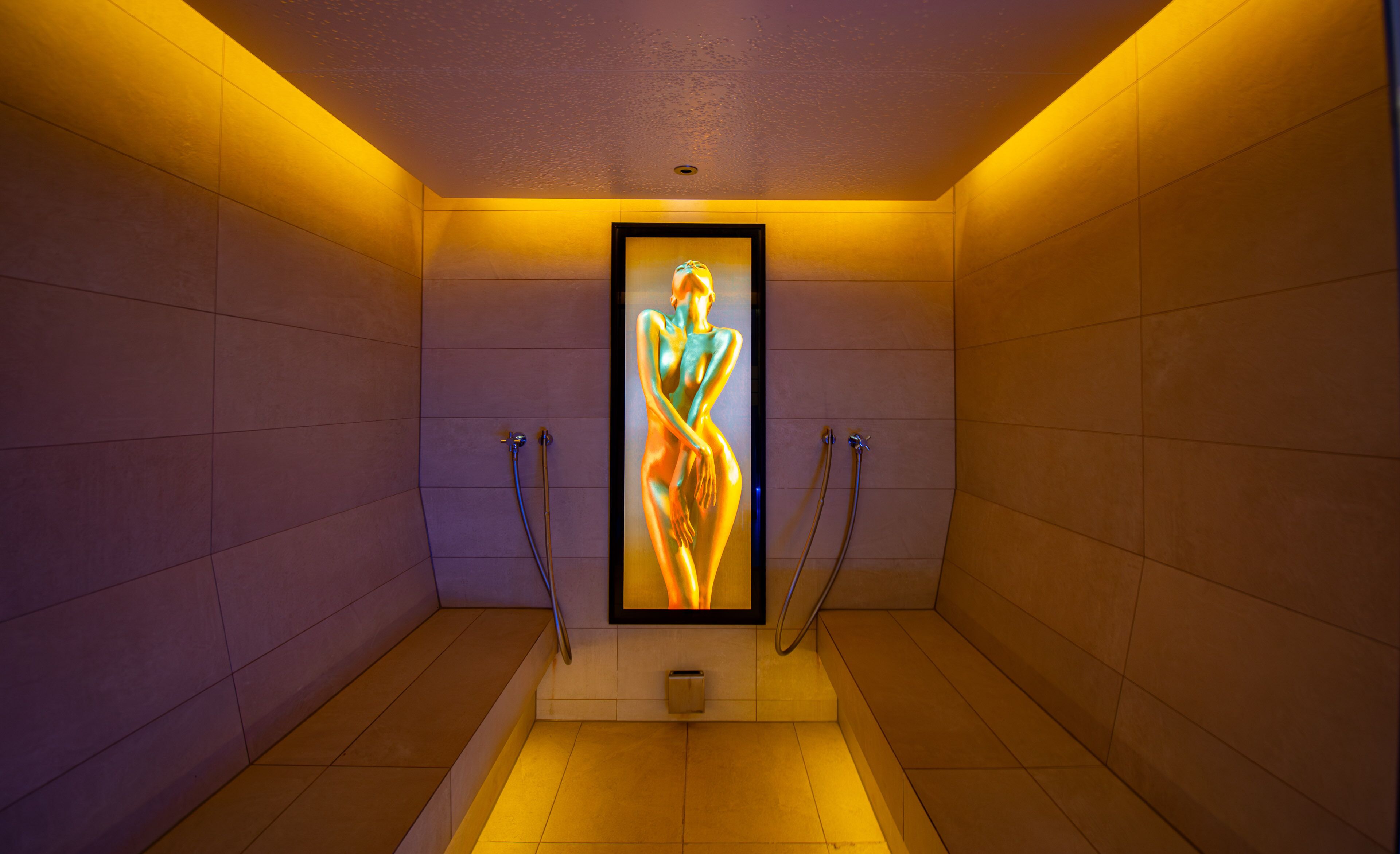 A narrow, tiled bathroom with a framed artwork of a human figure.