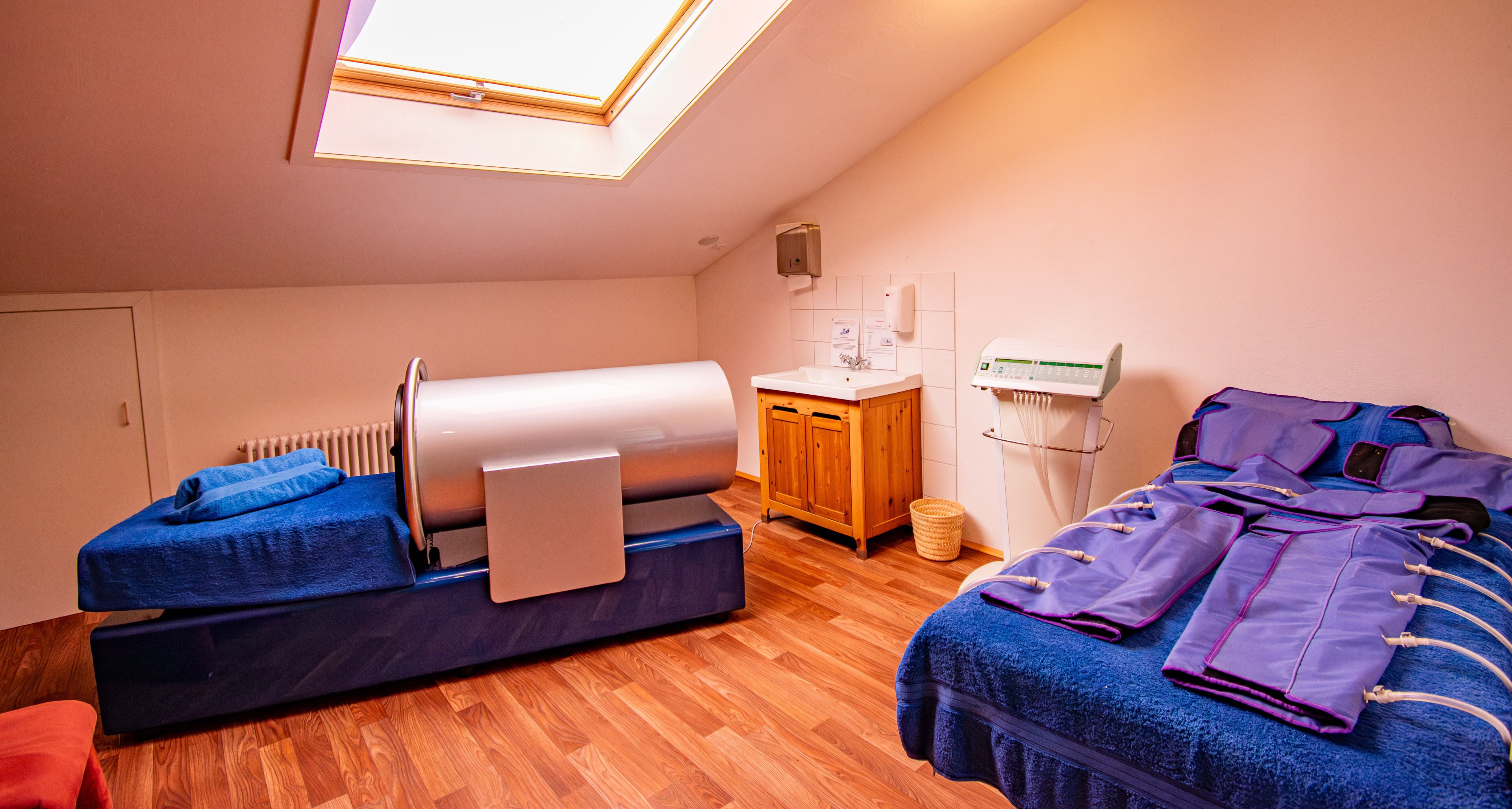 A room with a massage chair, a massage table with towels, a wooden cabinet, a radiator, and a skylight.