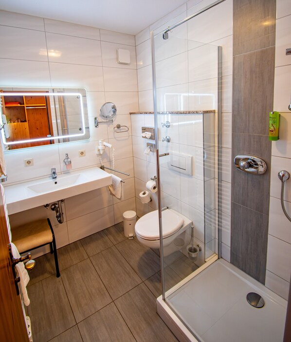 A modern bathroom with a glass-enclosed shower, a white sink, and a toilet.