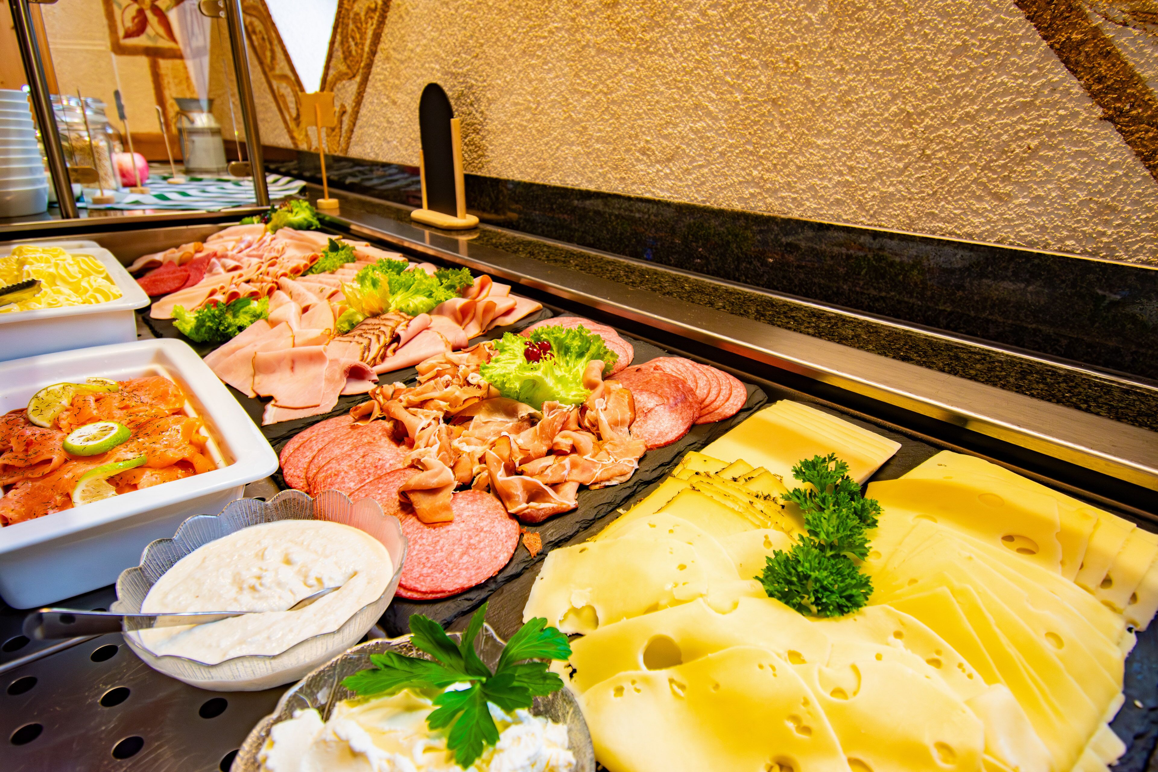A buffet with various food items including meats, cheeses, and vegetables.