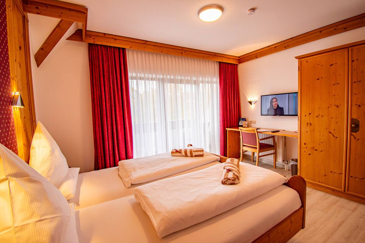 Une chambre d’hôtel avec deux lits, un bureau, une télévision et une armoire.