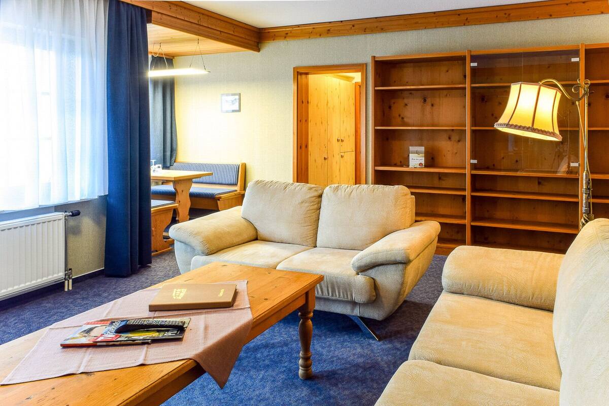 Une pièce chaleureuse avec un canapé, une table en bois sur laquelle sont posés des livres, une lampe et une bibliothèque.