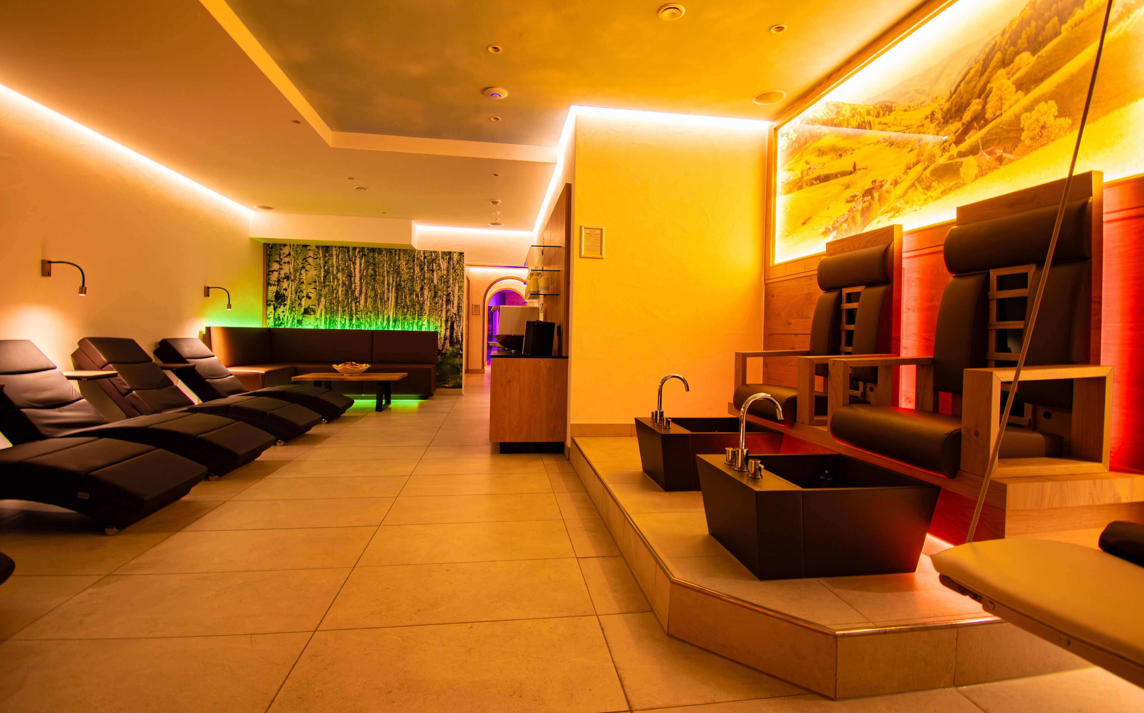 A modern spa with massage chairs, a reception area, and a wall with a nature-themed mural.