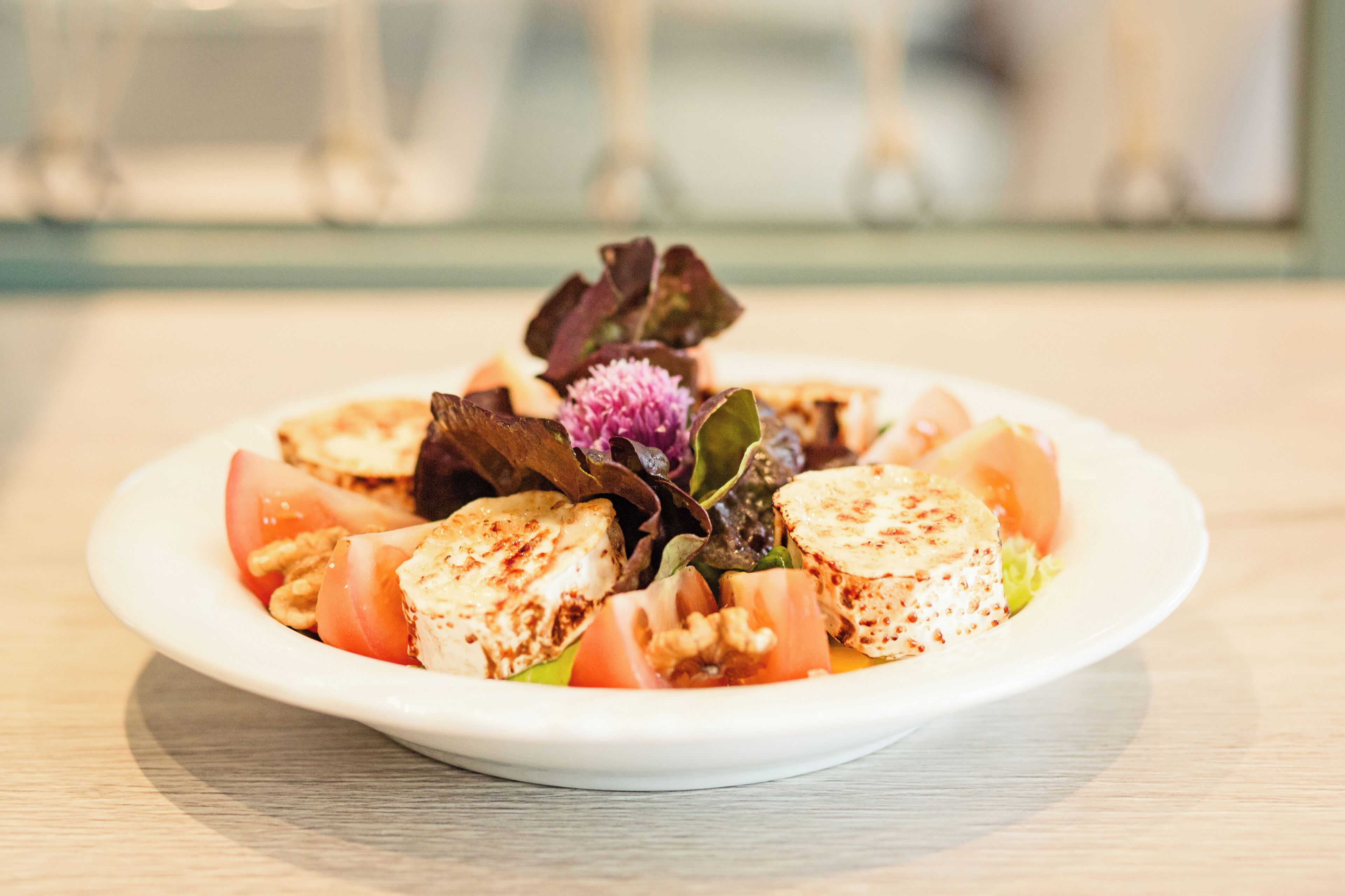 A plate of food with a salad, including tomatoes, walnuts, and a decorative flower.