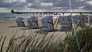 Beach chairs lined up on a sandy beach with a pier in the background. - Dünenschloß (Zinnowitz)