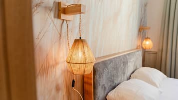 Una cama con cabecera, una lámpara de pared y una lámpara colgante.
