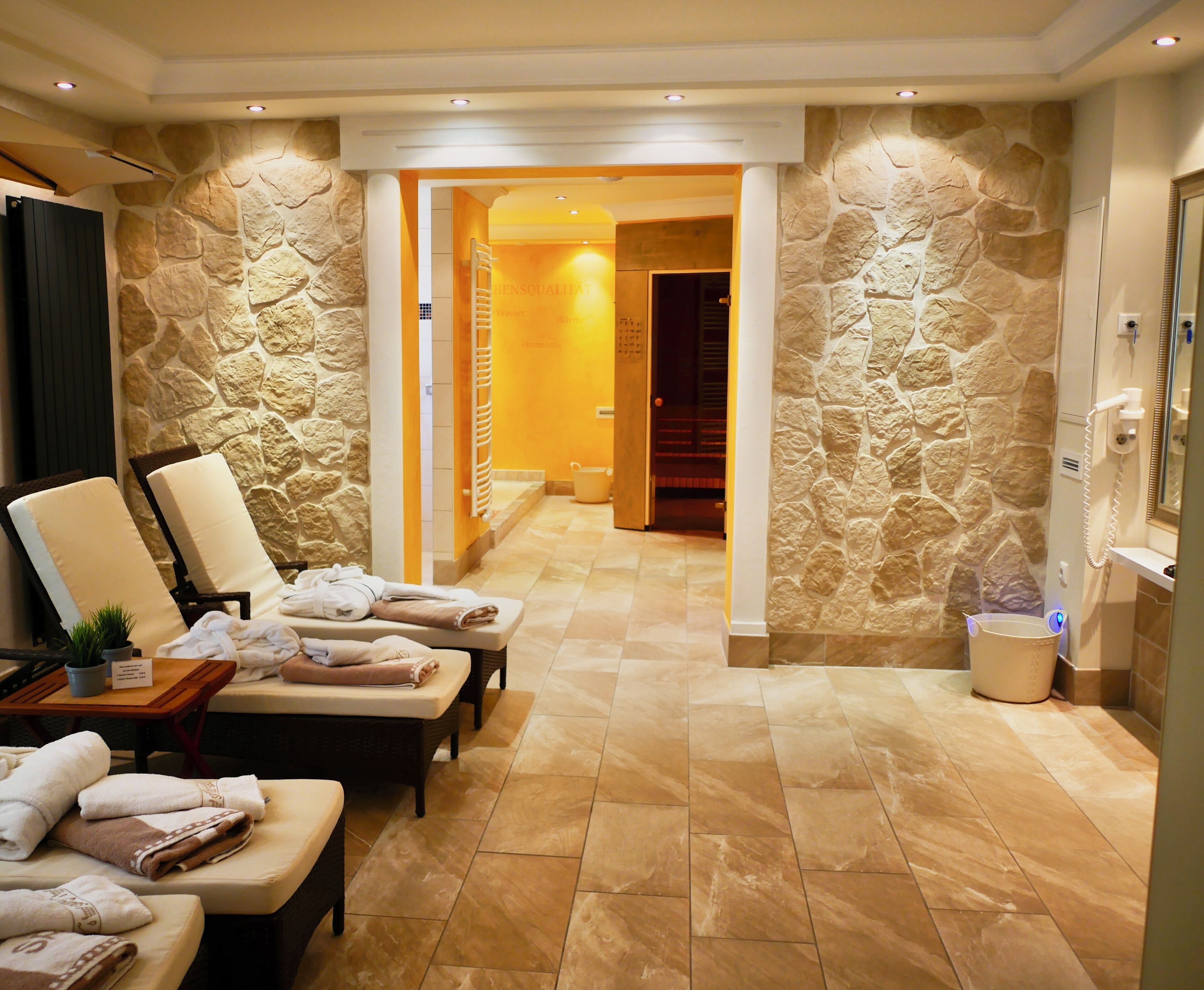 Zona de spa con paredes de piedra, sillones reclinables y toallas.