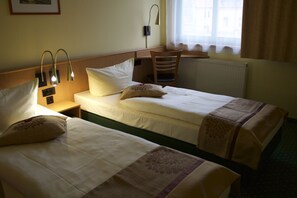 Habitación de hotel con dos camas, un escritorio y una silla.
