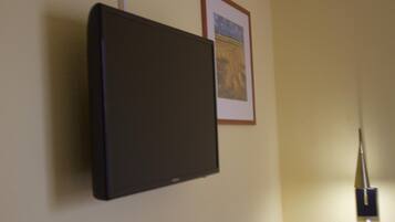 A flat-screen TV mounted on a wall with a framed picture above it.