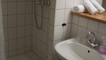 Une salle de bain avec une douche, un lavabo et un miroir.