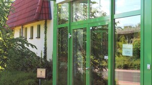 L'esterno dell'Hotel Acron, con porte in vetro a cornice verde, un cartello sopra l'ingresso e fioriere davanti.