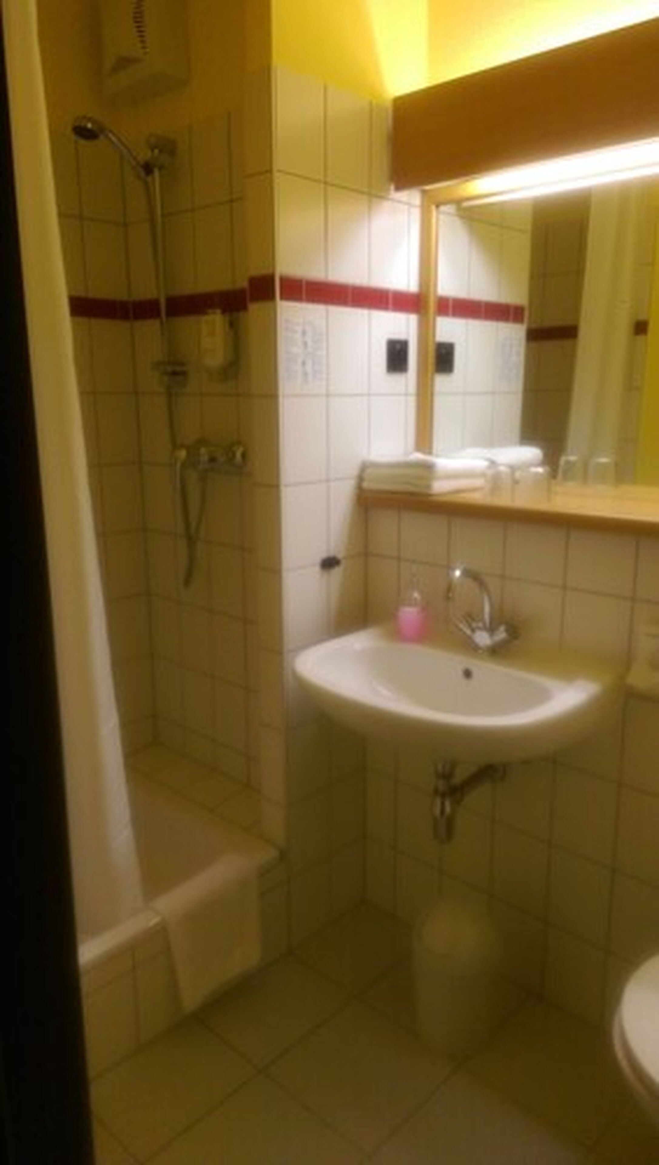 Een badkamer met douche, wastafel en toilet.