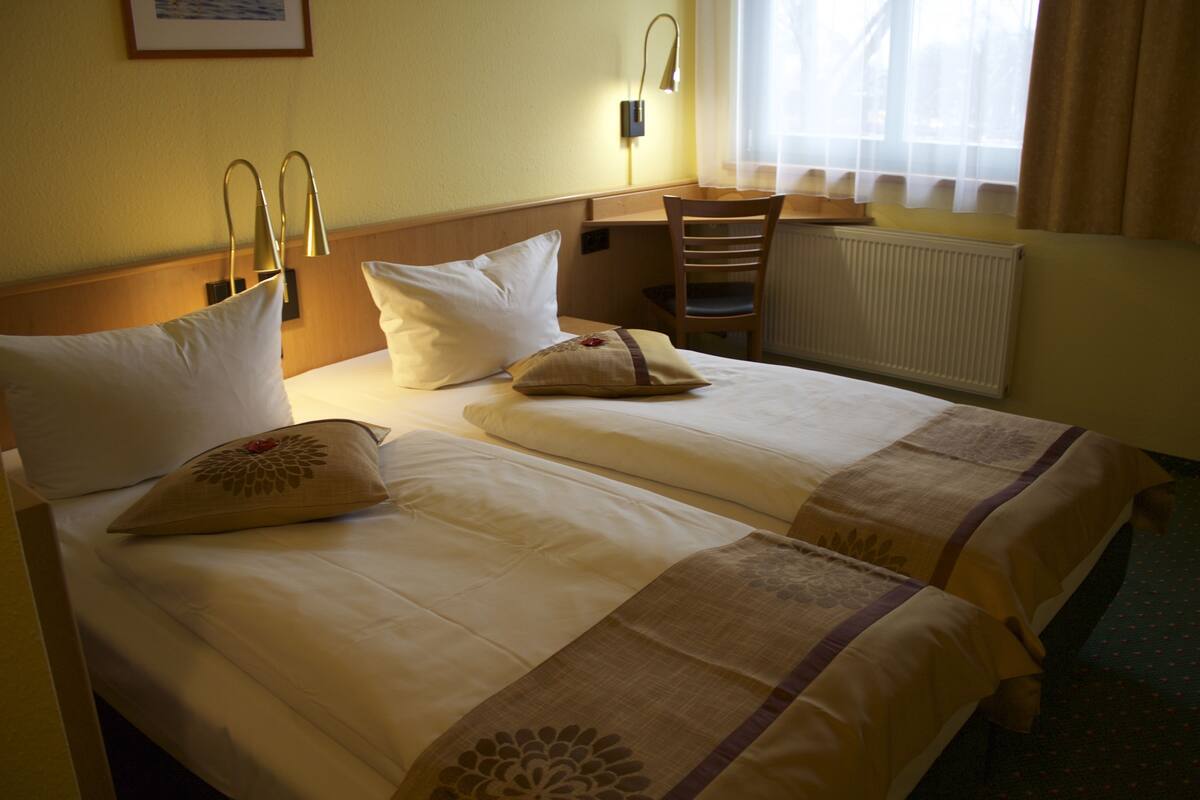 A hotel room with two beds, a desk, and a chair.