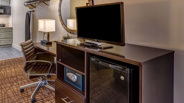 A hotel room with a desk, a flat-screen TV, a lamp, a chair, a microwave, and a refrigerator. - Surestay Hotel by Best Western Lovelock (Lovelock)