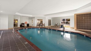 Una piscina interior con suelo de baldosas, un flotador y una silla junto a la piscina.