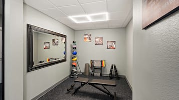 A small, well-lit room with a bench, exercise balls, and a mirror on the wall.