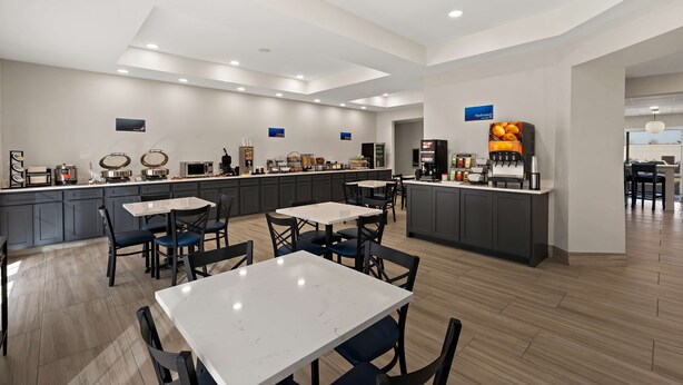 Un restaurante de hotel moderno con una barra central, diversas opciones de asientos y un diseño limpio y contemporáneo.