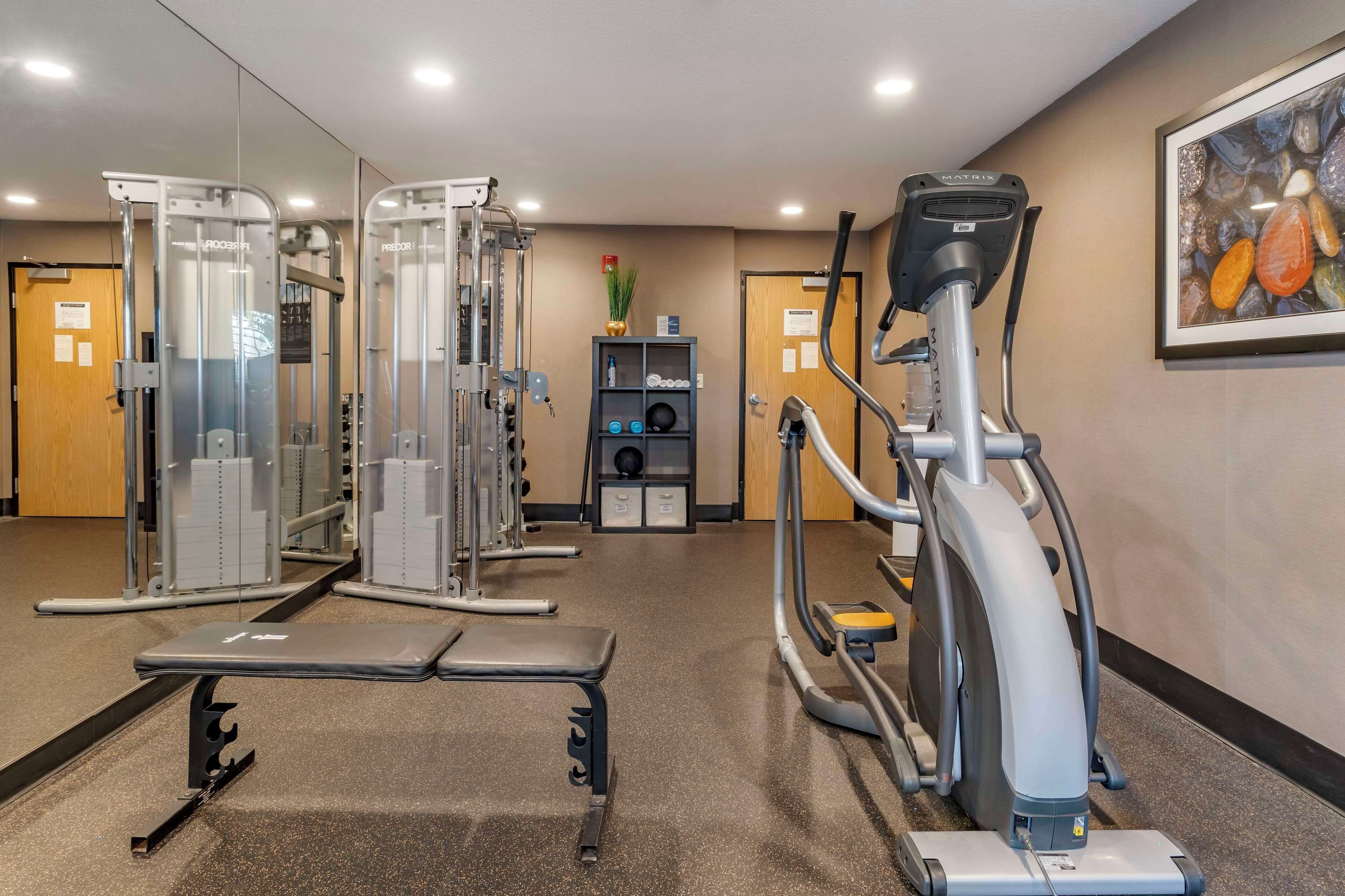 A gym with exercise equipment, a bench, and a mirrored wall.