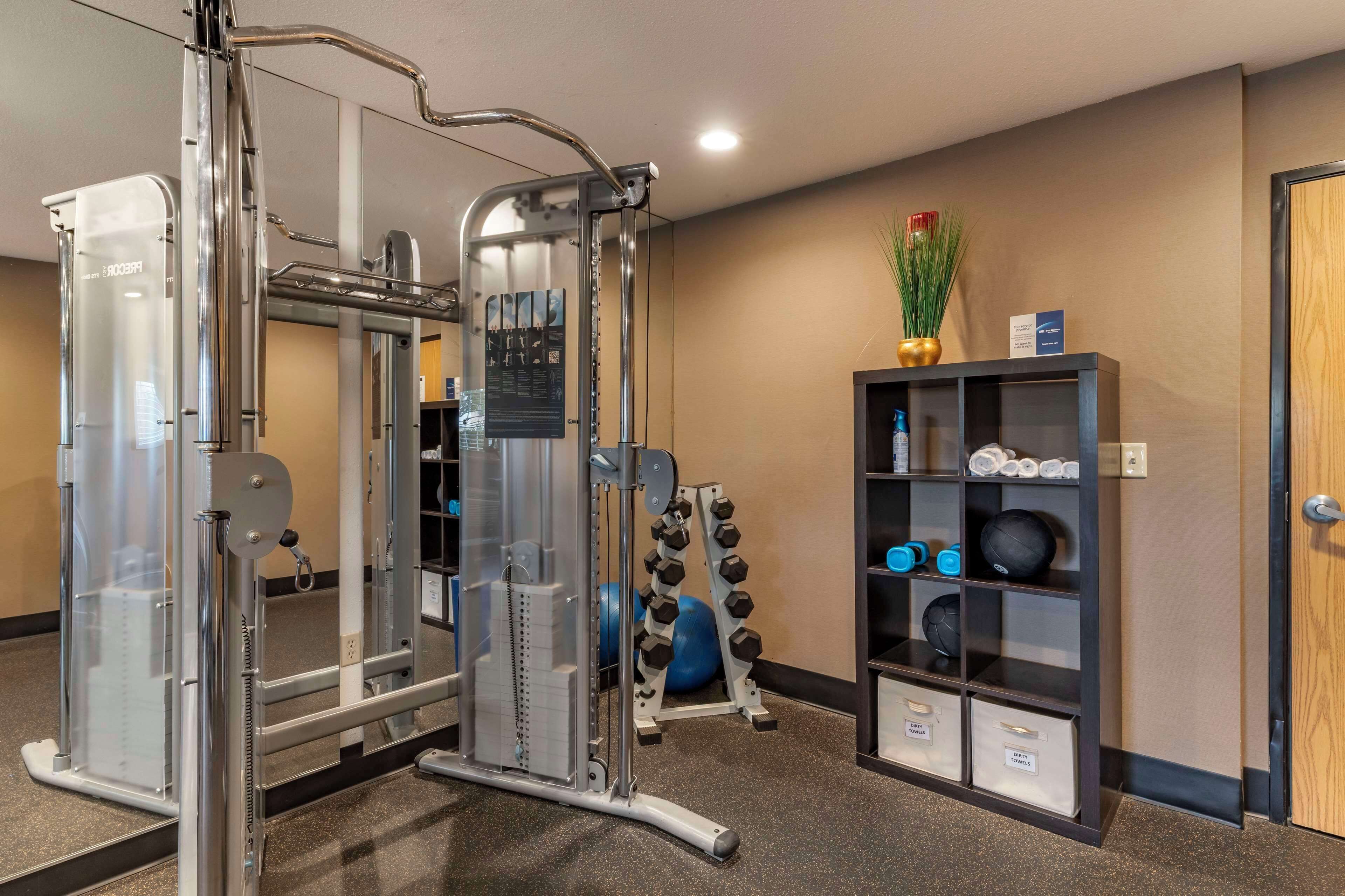 A gym with exercise equipment, a wall-mounted shelf with weights, and a door.