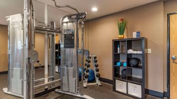A gym with exercise equipment, a wall-mounted shelf with weights, and a door.