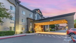 A hotel entrance with a covered driveway, marked parking spaces, and a sign indicating a garage. - Best Western Plus Vineyard Inn (Livermore)