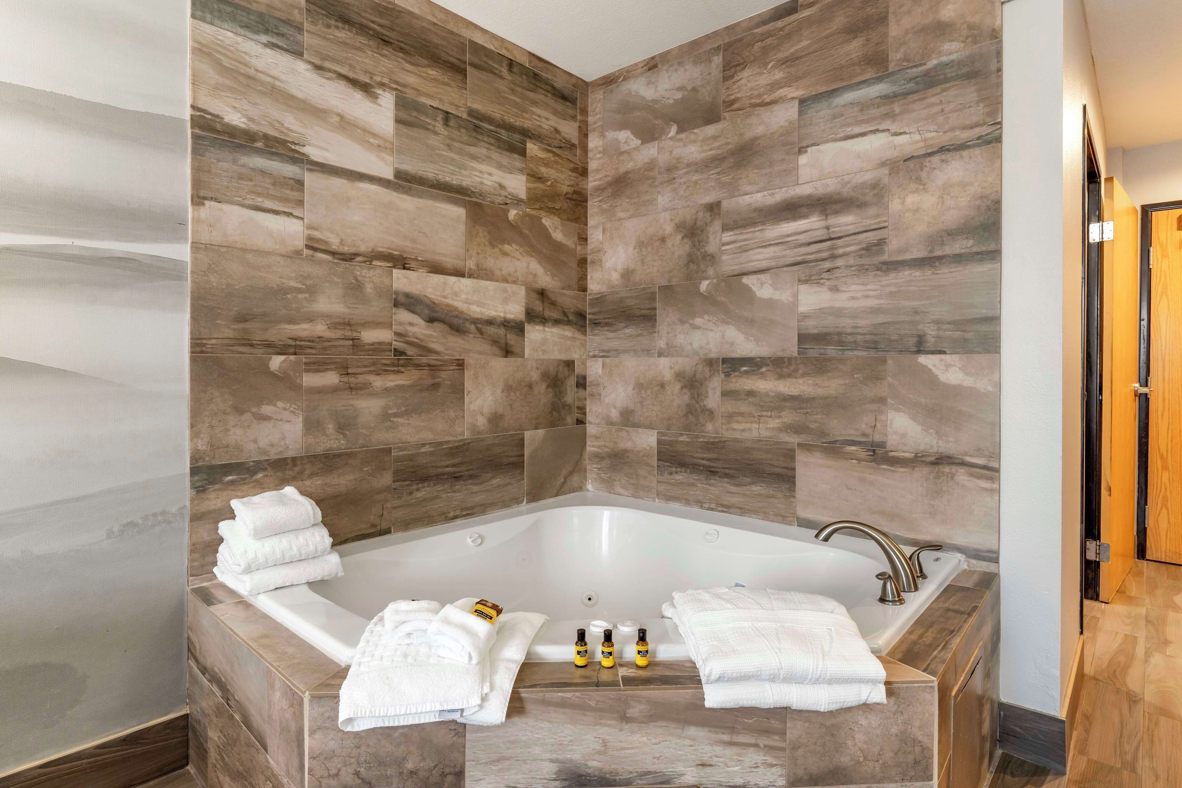 Un baño moderno con una bañera independiente, baldosas de mármol y toallas y artículos de aseo ordenados.